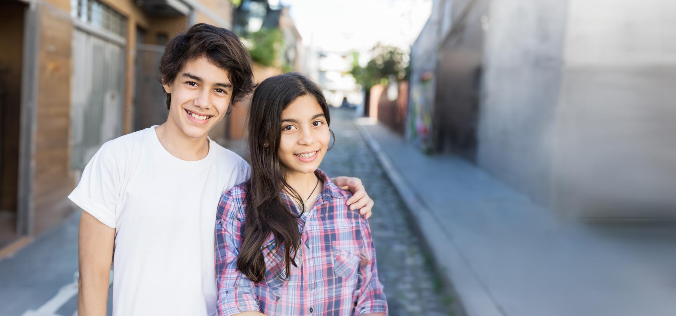 Teenage brother and sister smiling together outside